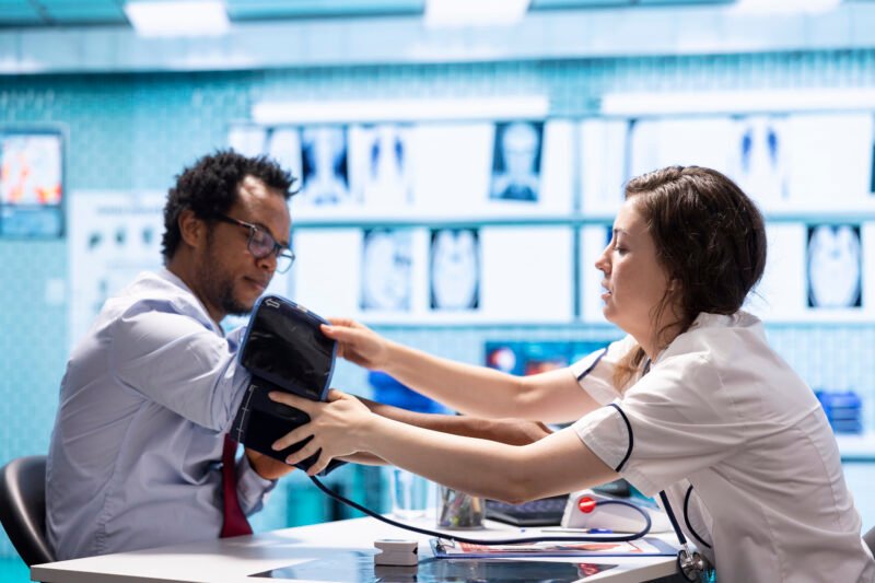 Physician doing a medical consultation with blood pressure monitor