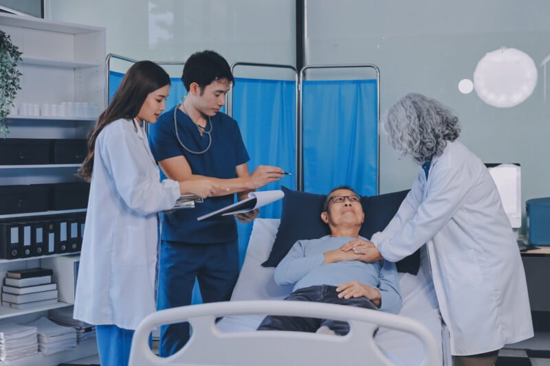 A team of doctors and nurses are working to treat a female patie A team of doctors and nurses are working to treat a female patient in the patient's room.