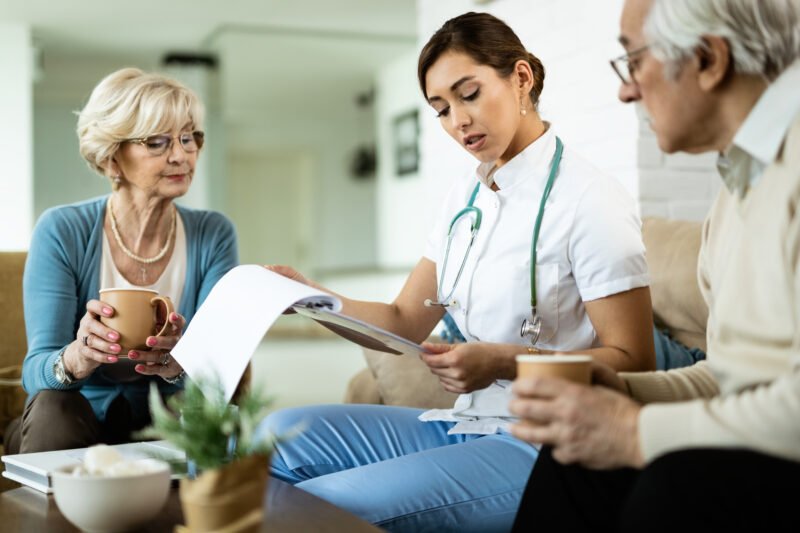 Female doctor reading medical reports of a senior couple while v