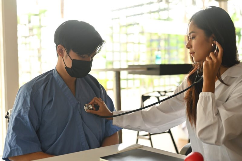 Photo of female doctor checks the patient’s heart pulse with a s Photo of female doctor checks the patient's heart pulse with a stethoscope in the modern health care center. Healthcare and medical concept.