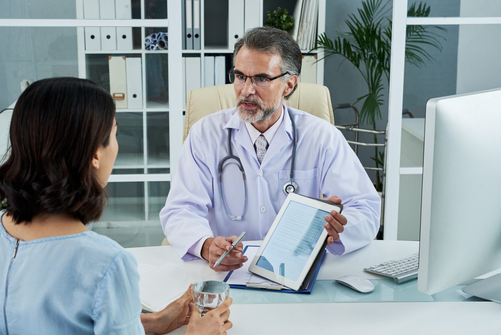 medium shot middle aged doctor explaining diagnosis via tablet pc scaled